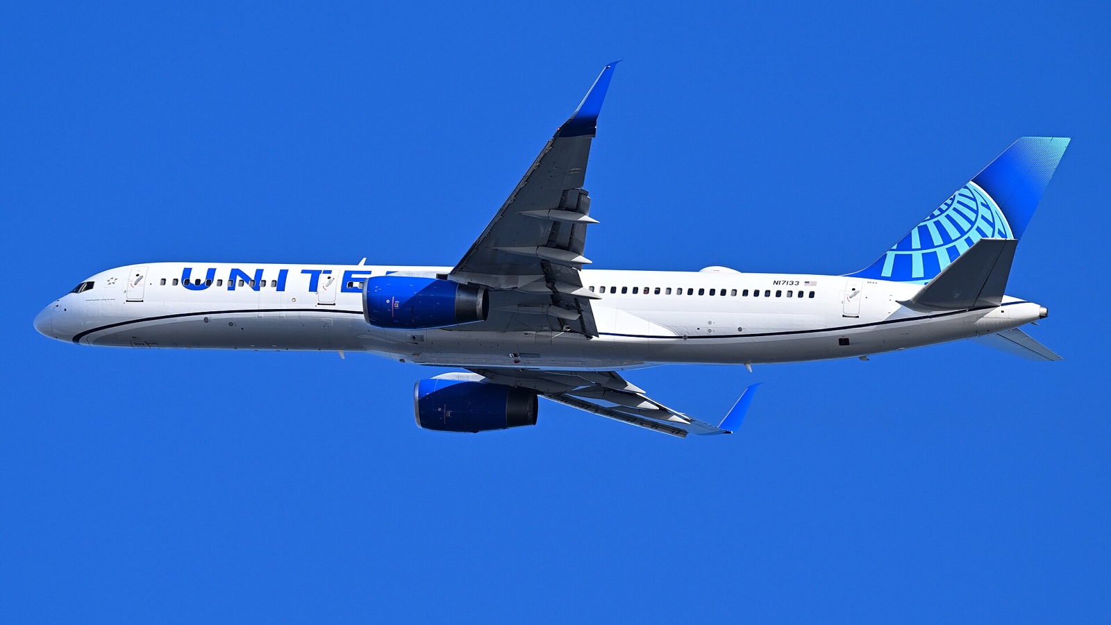 A United Airlines Boeing 757 in the current blue livery climbing through a clear sky