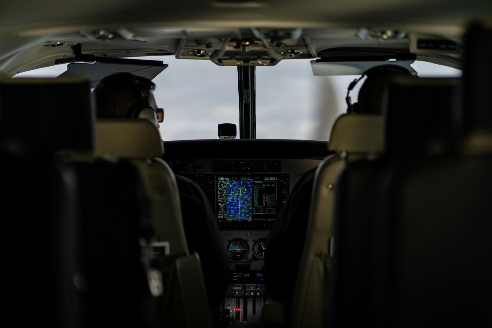 Two pilots seated in a softly lit cockpit above a glowing navigation display