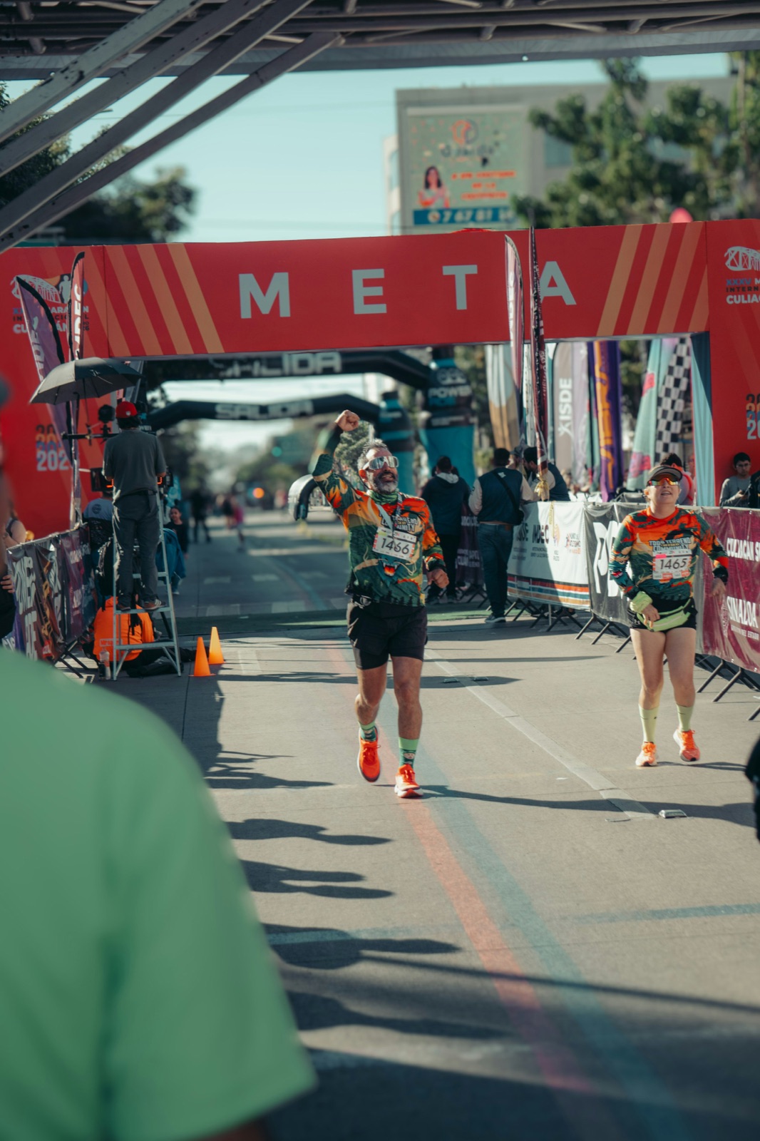 A runner raising his fist as he crosses a marathon finish line